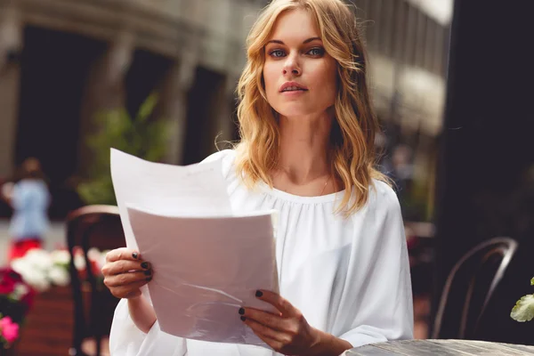 Блондинка на перерыве в кафе на открытом воздухе и с бумагами — стоковое фото
