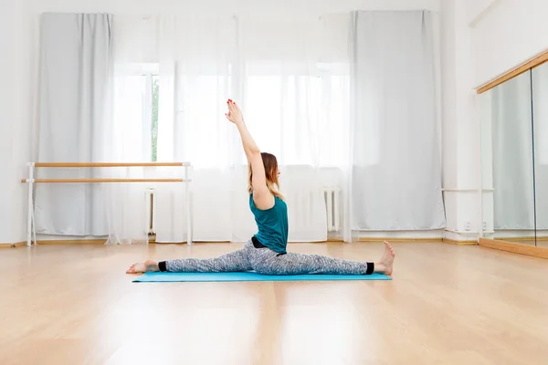 Flexible blonde girl sitting on twine, yoga posture, gymnastics — Stock Photo, Image