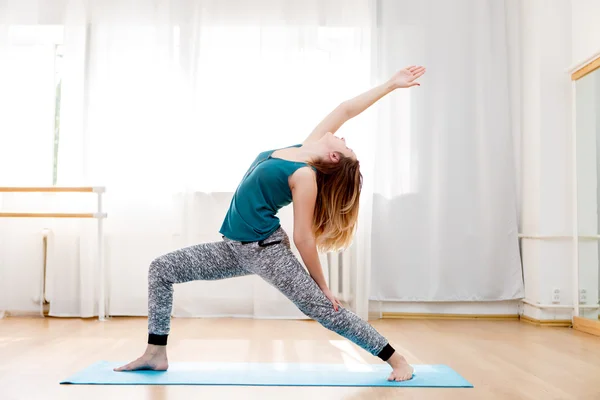 Young beautiful girl doing yoga in warrior pose, virabhadrasana — Stock Photo, Image