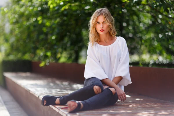 Elegante joven rubia hipster mujer descansando en el banco del parque —  Fotos de Stock