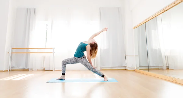 Parlak geniş Studio yoga yaparken genç güzel kadın