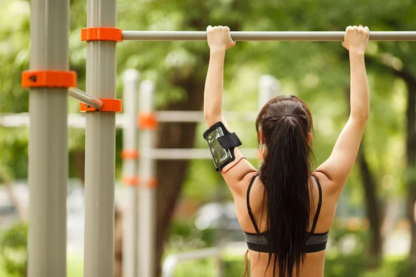 Fitness woman working out doing pull ups in park — Stock Photo, Image