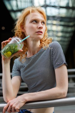 Çizgili gömlekli ferahlatıcı mojito içerken ince genç kadın