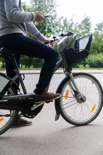 Rowerzysta siedzi na rower i przeglądania w telefonie — Zdjęcie stockowe