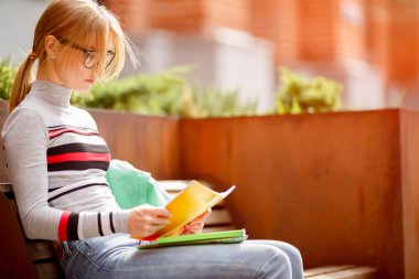 bankta oturan gözlüklü genç kadın