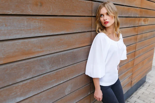 Retrato de una hermosa mujer rubia apoyada en tablas de pared — Foto de Stock