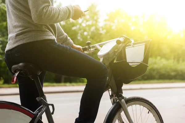 Mannen i casual kläder ridning cykel och fokuserar på telefon — Stockfoto