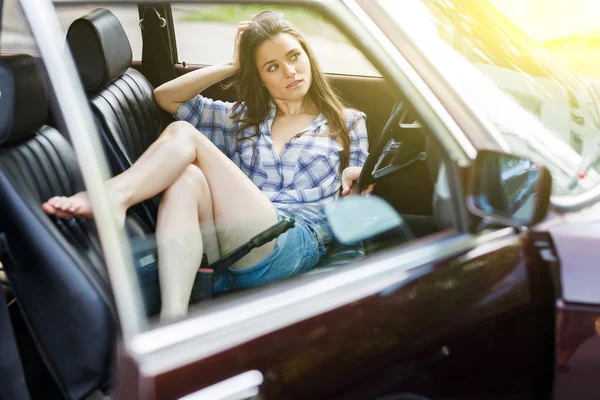 Brunette is sitting in open car — Stock Photo, Image