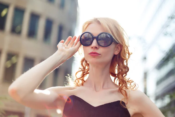 Ginger woman in black sunglasses on street, tinted photo — Stock Photo, Image