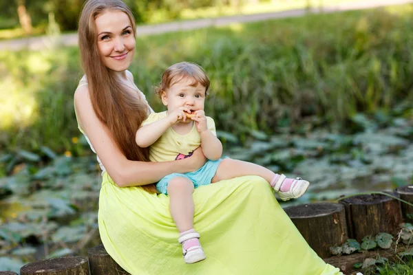 Happy mother and daughter on stump in park — Stock Photo, Image