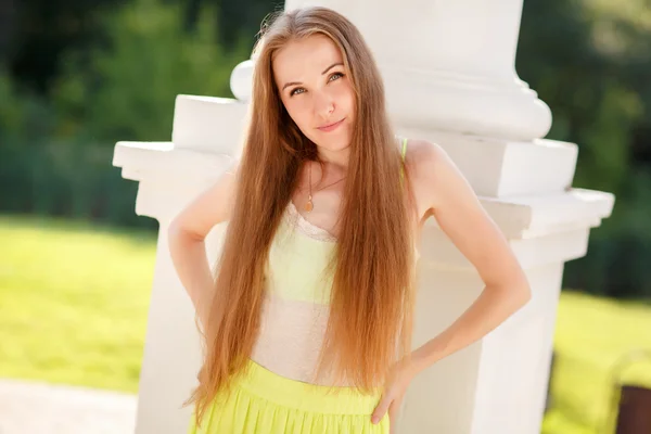 Mooie jonge vrouw op de kolom in de zomer park — Stockfoto
