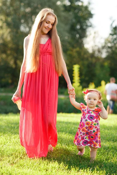 Mom in dress holding hand of daughter go through park — Stock Photo, Image
