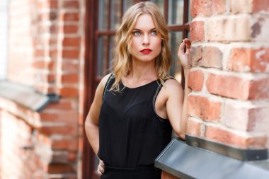 Güzel ve şık sarışın kadının sonraki tuğla duvar ile poz