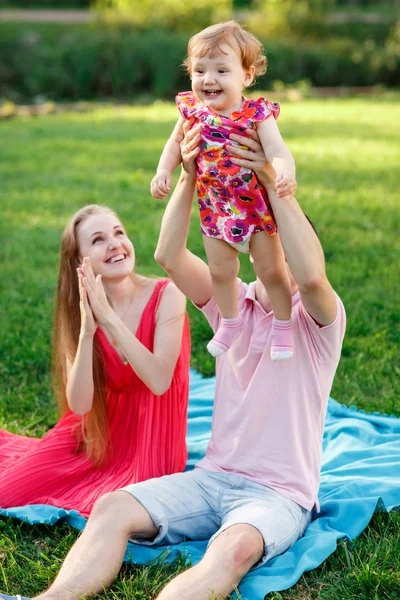 Pappa håller baby dotter i armar sitter på pläd — Stockfoto
