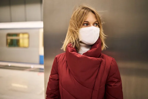Жінка в масці і червоне пальто в метро — стокове фото