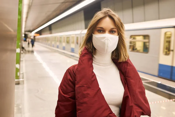 Woman in mask and red coat in the subway — Stock Photo, Image