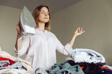 Genç kız evde kıyafetlerini ütülemeden önce meditasyon yapıyor.