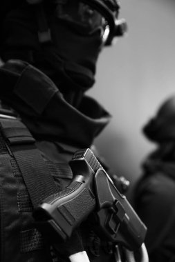 Asker kurşun geçirmez yelek giyerken modern silahı elinde tutuyor. Üniforma.