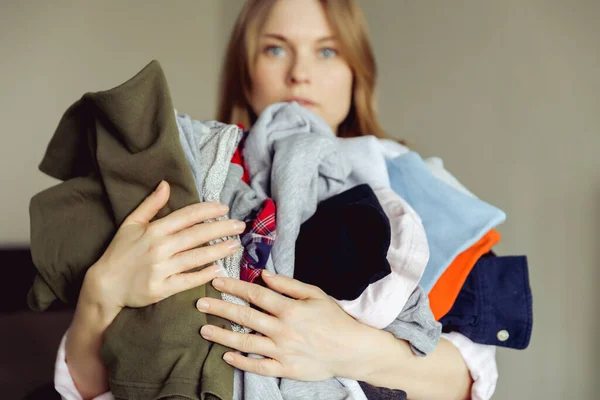 Young woman holding a huge pile of clothes — Stock Photo, Image