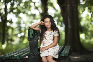Parkta bankta oturmuş gülümseyen güzel kız