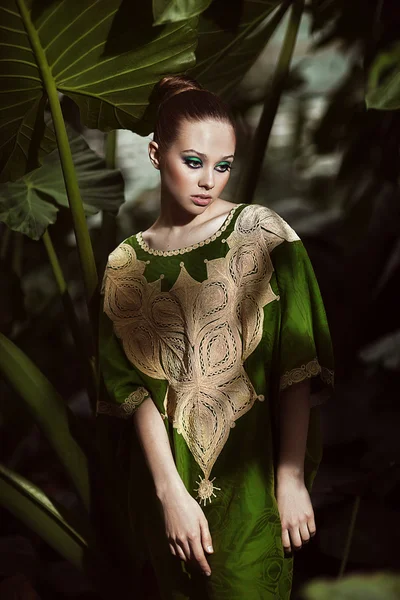 Beautiful woman in green dress standing in exotic forest. — Stock Photo, Image