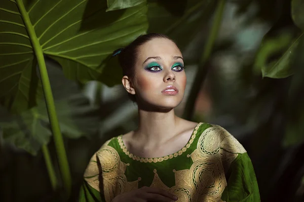 Portrait of beautiful woman in green dress standing in exotic forest. — Stock Photo, Image