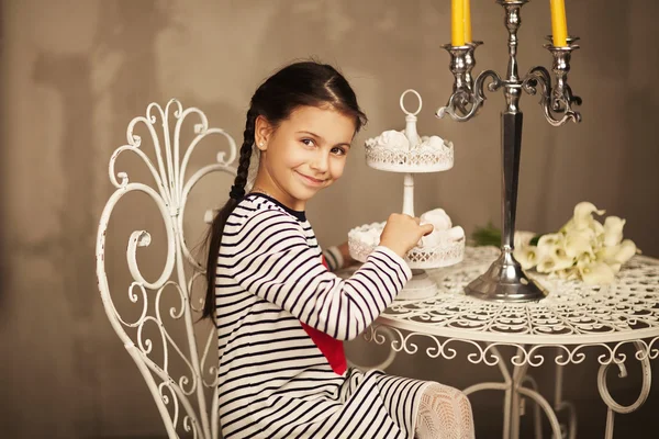 Schönes kleines Mädchen sitzt und Kuchen essen geht Stockbild