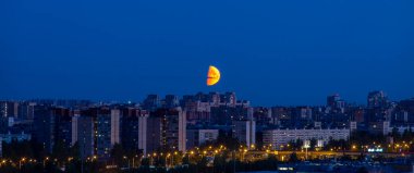 Şehrin üzerinde dramatik büyük kırmızı ay. Yaz gecesi. Gökyüzü açık.