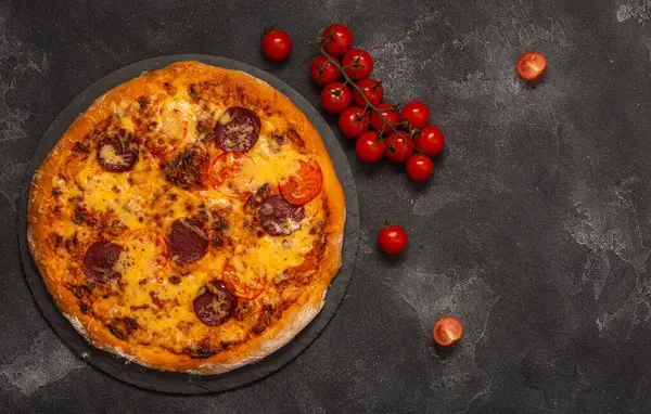 Deliciosa pizza de pepperoni e ingredientes sobre fondo de hormigón negro. Vista superior de la pizza de pepperoni picante. Con espacio de copia para texto. Acostado. Banner. — Foto de Stock