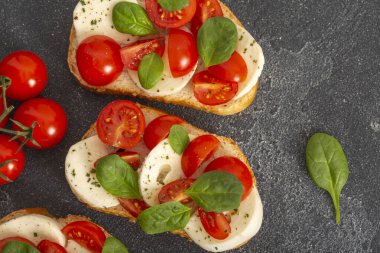 Caprese bruschetta tostları mozzarella, kiraz domatesleri ve taze bahçe fesleğeni. Geleneksel İtalyan aperatifi veya aperatifi, antipasto. Kopyalama alanı olan üst görünüm. Düz yatıyordu.