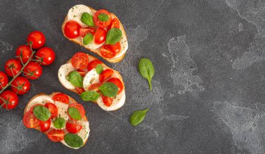 Caprese bruschetta tostları mozzarella, kiraz domatesleri ve taze bahçe fesleğeni. Geleneksel İtalyan aperatifi veya aperatifi, antipasto. Kopyalama alanı olan üst görünüm. Düz yatıyordu.