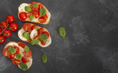 Caprese bruschetta tostları mozzarella, kiraz domatesleri ve taze bahçe fesleğeni. Geleneksel İtalyan aperatifi veya aperatifi, antipasto. Kopyalama alanı olan üst görünüm. Düz yatıyordu.