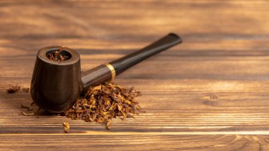 Ahşap arka planda sigara piposu ve tütün.