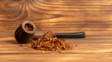 Ahşap arka planda sigara piposu ve tütün.