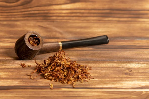 Smoking pipe and tobacco on wooden background