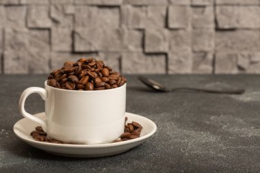 Üzerinde kahve taneleri olan beyaz bir kupa. Yan görünüm