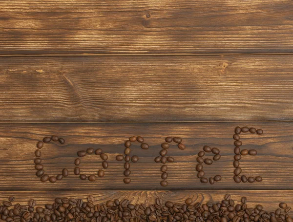 Die Inschrift Kaffee aus Bohnen auf einem hölzernen Hintergrund. Kopierraum. Flache Lage — Stockfoto