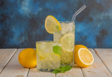 İki bardak soğuk, ferahlatıcı limonata. Limon ve naneli mojito kokteyli. Ahşap arka planda buzlu içecek..