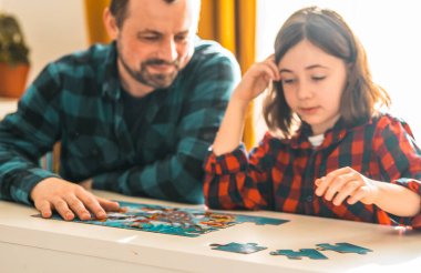 Baba ve kızı evde yapboz yapıyor. Aile zamanı kavramı.