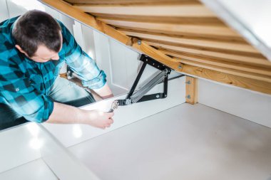 Adam evde mobilya anahtarı kullanarak yatak kaldırma mekanizması kuruyor. DIY Montaj Mobilyaları.