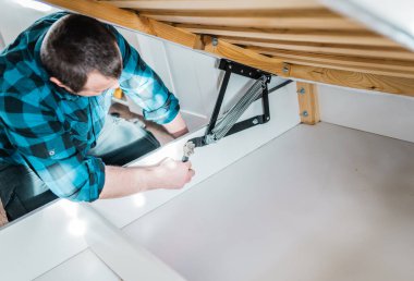 Adam evde mobilya anahtarı kullanarak yatak kaldırma mekanizması kuruyor. DIY Montaj Mobilyaları.