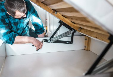 Adam evde mobilya anahtarı kullanarak yatak kaldırma mekanizması kuruyor. DIY Montaj Mobilyaları.