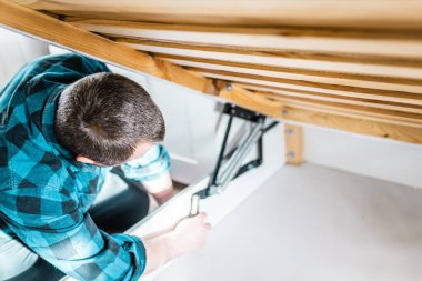Adam evde mobilya anahtarı kullanarak yatak kaldırma mekanizması kuruyor. DIY Montaj Mobilyaları.