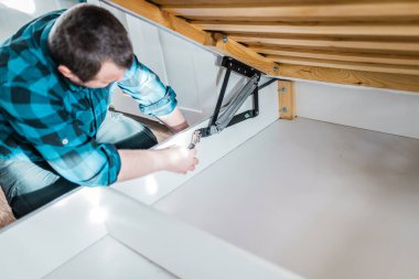 Adam evde mobilya anahtarı kullanarak yatak kaldırma mekanizması kuruyor. DIY Montaj Mobilyaları.