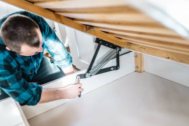 Adam evde mobilya anahtarı kullanarak yatak kaldırma mekanizması kuruyor. DIY Montaj Mobilyaları.