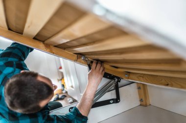 Adam evde mobilya anahtarı kullanarak yatak kaldırma mekanizması kuruyor. DIY Montaj Mobilyaları.