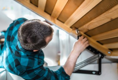 Adam evde mobilya anahtarı kullanarak yatak kaldırma mekanizması kuruyor. DIY Montaj Mobilyaları.