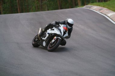 Asfalt yolda motosiklet süren bir adam. Siyah-beyaz spor motosikletinde motosikletçi.