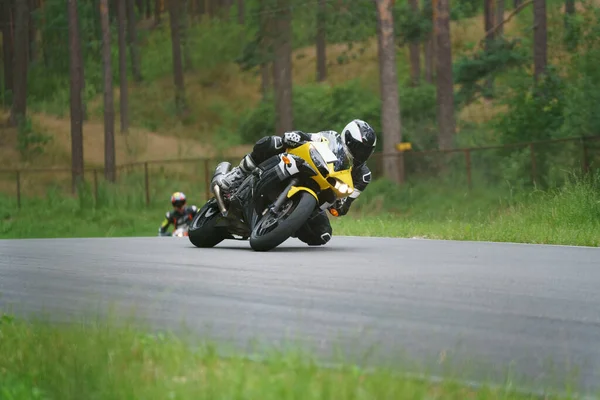 アスファルトの道路でバイクに乗る男 黄色のスポーツバイクで黒のスーツでオートバイ — ストック写真