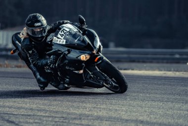 Asfalt yolda motosiklet süren bir adam. Siyah-beyaz spor motosikletinde motosikletçi.